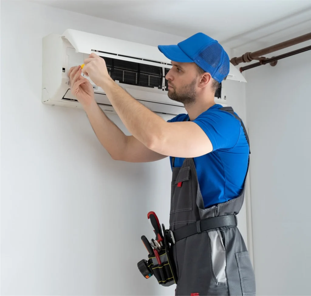 Professional HVAC technician installing a white wall-mounted ductless mini-split air conditioning system in a Boulder home.
