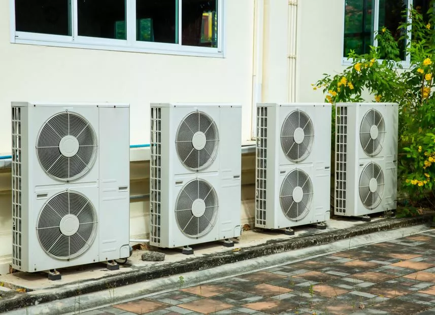 A row of four high-capacity dual-fan heat pump units installed on a concrete pad for a commercial building in Boulder.