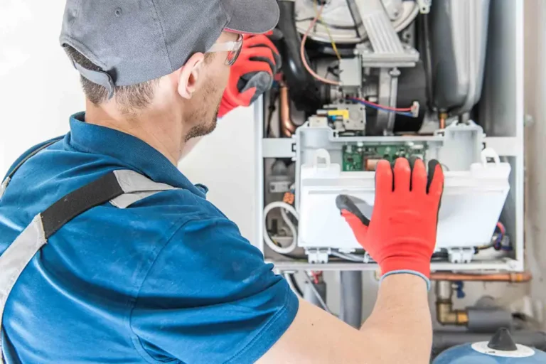 A professional HVAC technician in safety gear performing a diagnostic check and maintenance on a residential boiler system in Boulder.